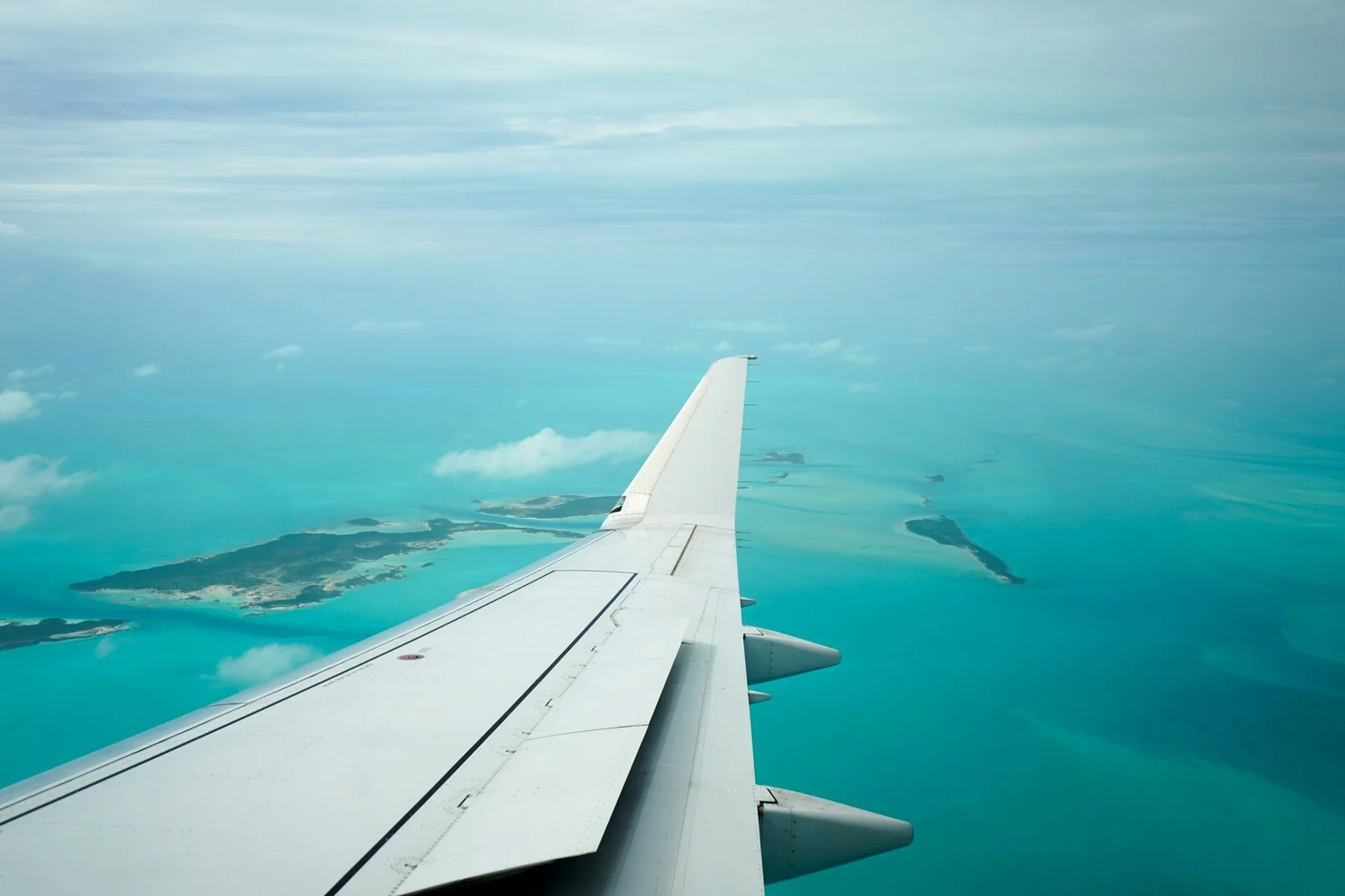 Aircraft wing over the turquoise banks on approach to Andros
