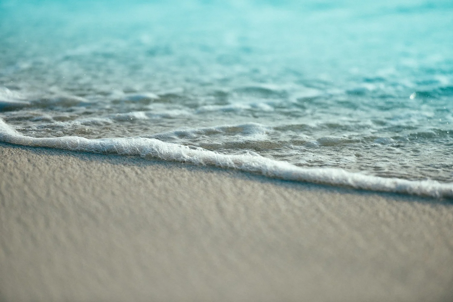 Gentle wave washing over white sand